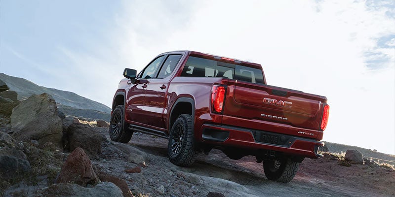 Red Sierra 1500 going uphill outside in front of a mountain that is covered in snow